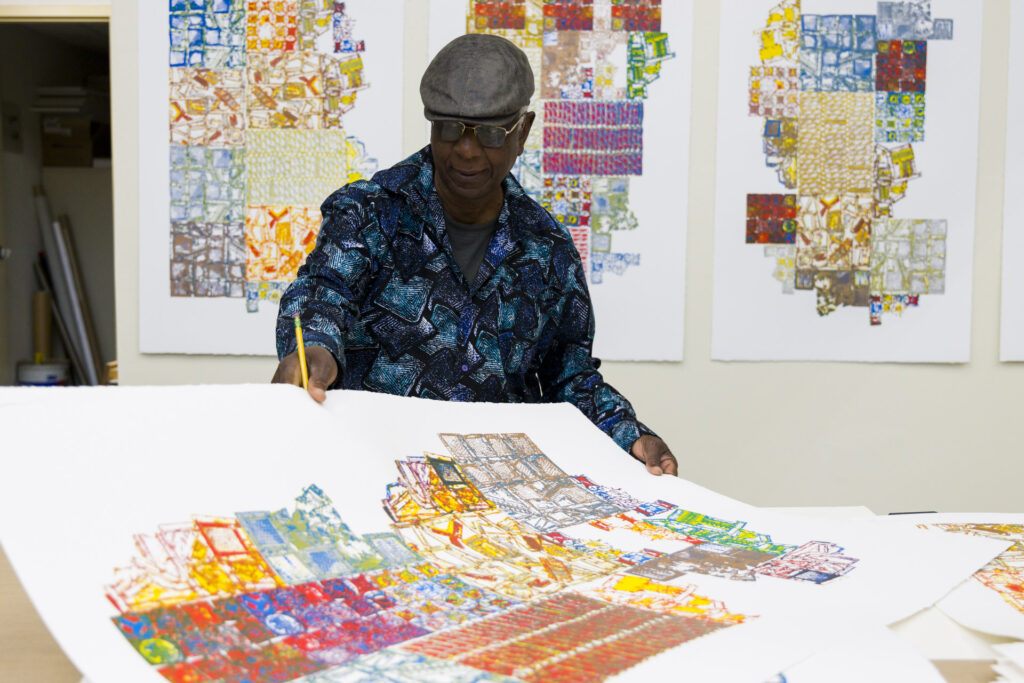 El Anatsui signing prints in the workshop.